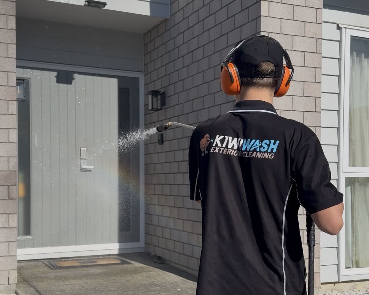 Kiwi Wash team member applying cleaning solution to a brick and cladding home